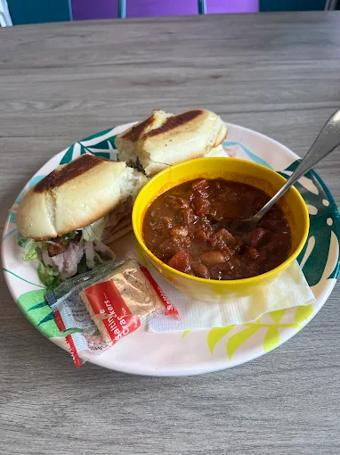 Sandwich on a hoagie roll with a bowl of chili on a patterned plate